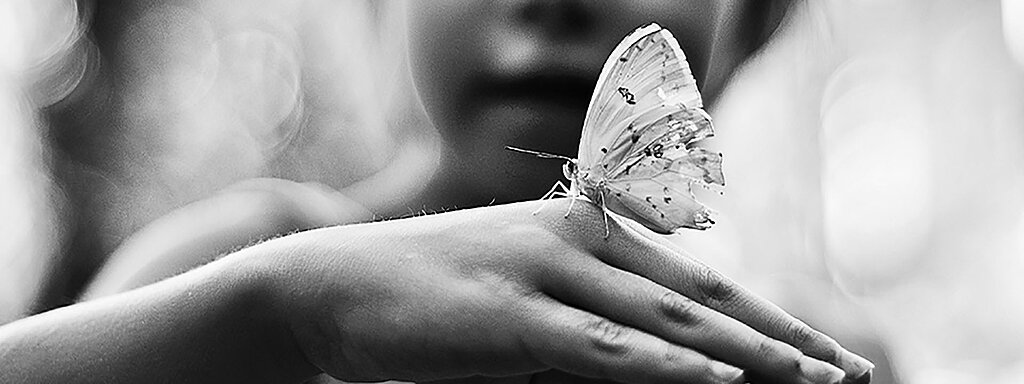 Kind mit Schmetterling auf der Hand